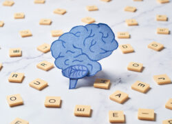 Mózg na tle rozsypanych liter z gry scrabble. Pokazuje, ze chodzi o trudności związane z literami i czytaniem.